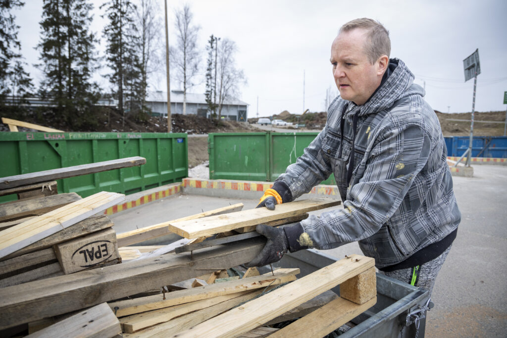 Mies purkamassa puujätteitä peräkärrystään