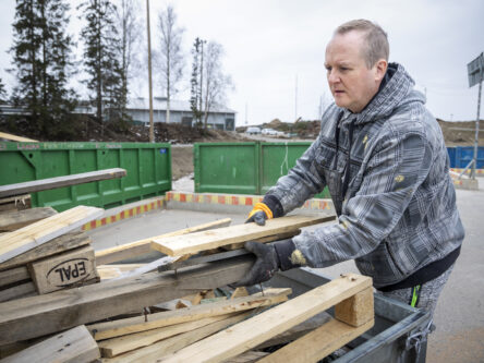 Mies purkamassa puujätteitä peräkärrystään