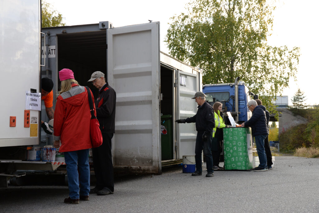 Ihmisiä tuomassa vaarallisia jätteitä kierrätysautolle
