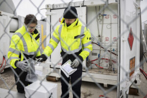 Nainen ja mies pakkaavat biokaasunäytettä kuljetuslaatikkoon