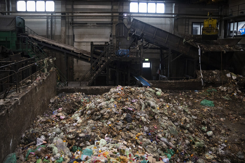 Suuret röykkiöt biojätettä sisällä laitoksessa