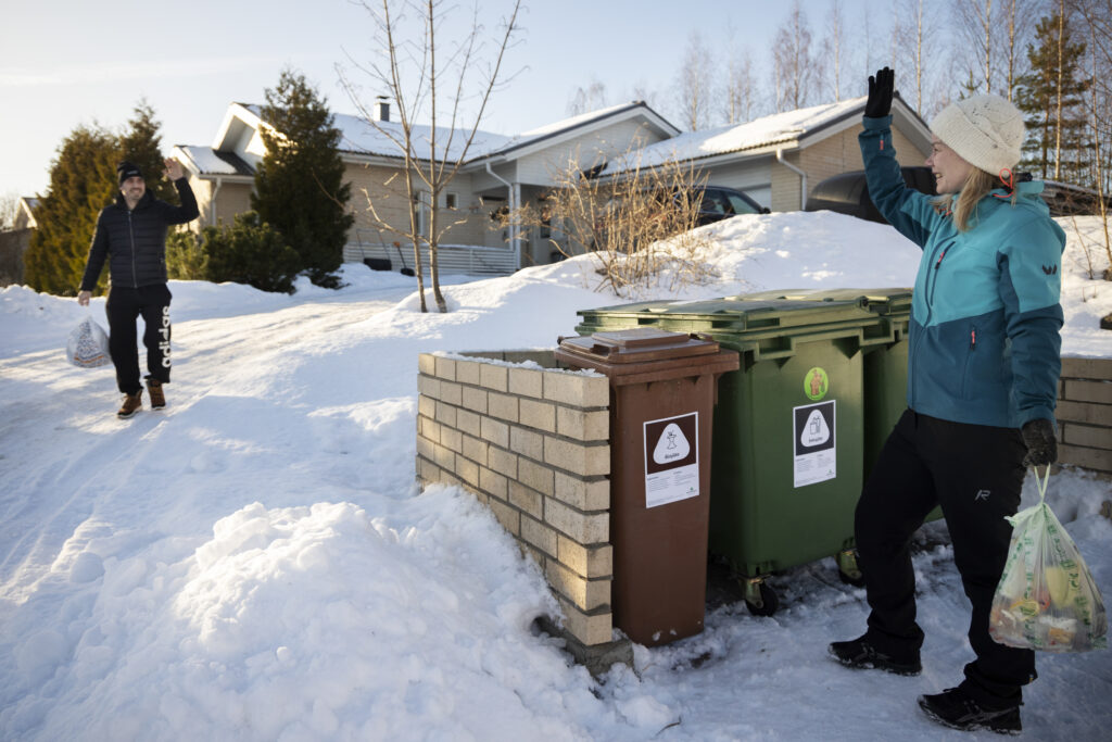 Mies ja nainen tervehtivät toisiaan jäteastioilla