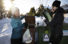 Nainen laittaa roskapussia biojäteastiaan, mies sekajätteisiin