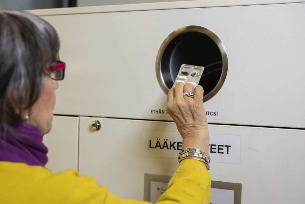 Nainen laittaa lääketabletteja palautusreiästä