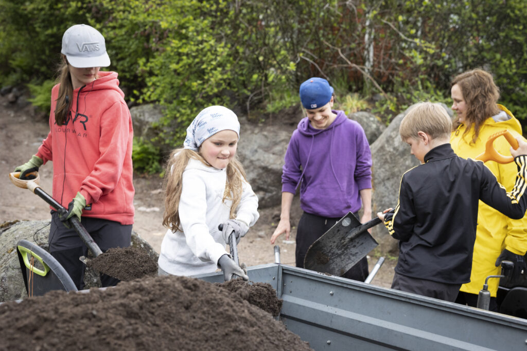 Koko perhe purkamassa multakuormaa peräkärryistä
