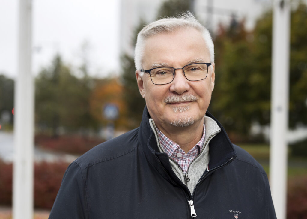 Mies hymyilee kainosti kameralle