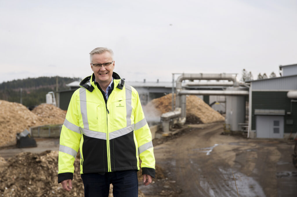 Mies seisoo kompostointilaitoksen lähettyvillä, taustalla näkyy kasoja puuhaketta