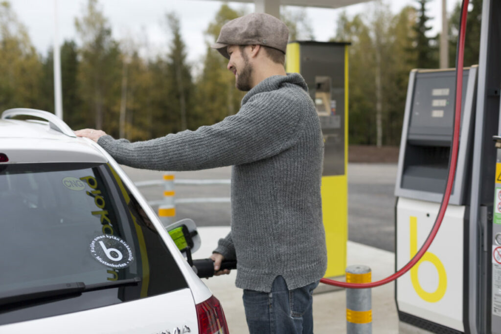 Mies tankkaa valkoista biokaasuautoaan