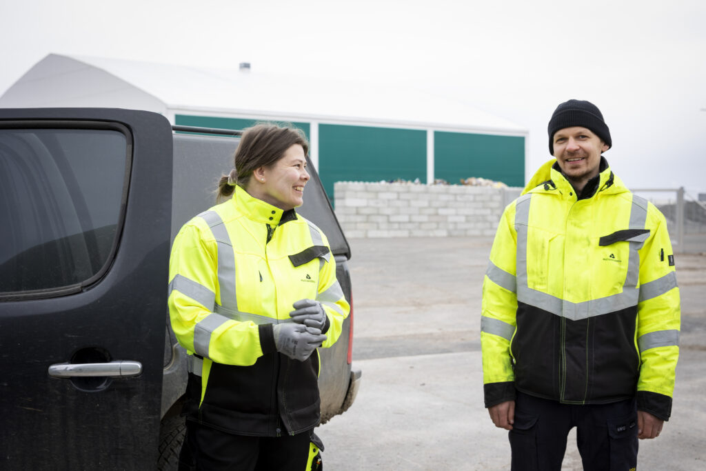 Nainen katsoo hymyillen miestä, kummallakin on huomiovaatteet