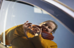 Nainen näyttää käsillään sydäntä, joka heijastuu auton ikkunasta