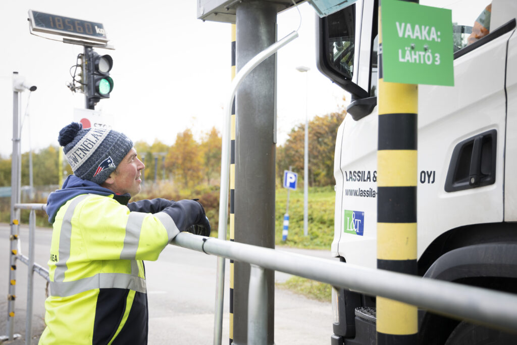 Mies keskustelee jäteauton kuskin kanssa jätekeskuksen jätevaa'an luona