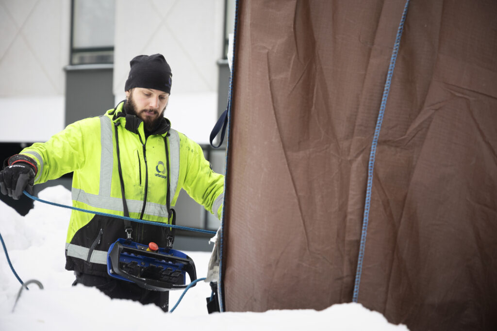 Jäteauton kuljettaja valmistautuu tyhjentämään syväkeräysastiaa.