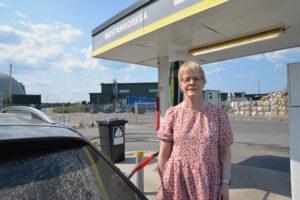 Mustankorkean talous- ja hallintopäällikkö Tiina Pakarinen seisoo autonsa vieressä biokaasuasemalla.