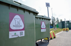 Kaksi vihreää jäteastiaa, joissa violetit poistotekstiilin jätetarrat. Yläpuolella lukee kierrätyspisteen numero 31.