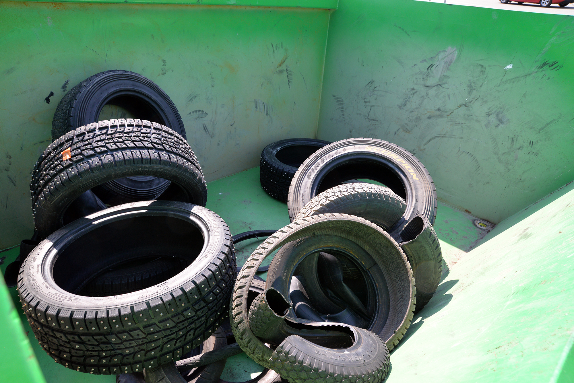 Vanteettomia renkaita vihreällä jätelavalla.