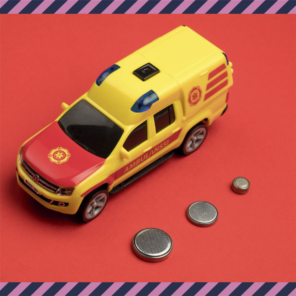 Lasten leikkiambulanssi ja sen vieressä paristot.
