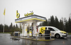 Biokaasuauto on pysähtyneenä Mustankorkean jätekeskuksen tankkausasemalla. Myös pakettiautossa on biokaasun keltaiset tarrat. Sää on melko harmaa ja sateinen.