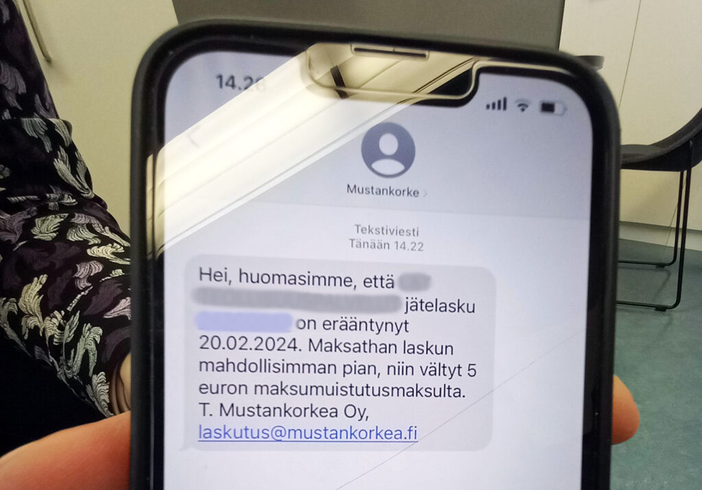 Kännykän ruudulla on tekstiviesti, jossa lukee: Hei, huomasimme, että jätelasku on erääntynyt 20.2.2024. Maksathan laskun mahdollisimman pian, niin vältyt 5 euron maksumuistusmaksulta. T. Mustankorkea Oy, laskutus@mustankorkea.fi