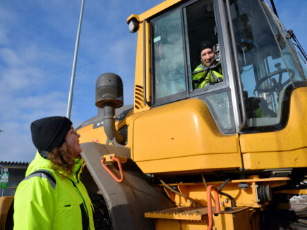 Nainen katsoo miestä ylempänä pyöräkoneessa. Kumpaakin hymyilyttää.
