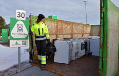 Huomiovaatteet päällä oleva nainen on imuri kädessä ja katsoo sen vieressä olevia helloja.