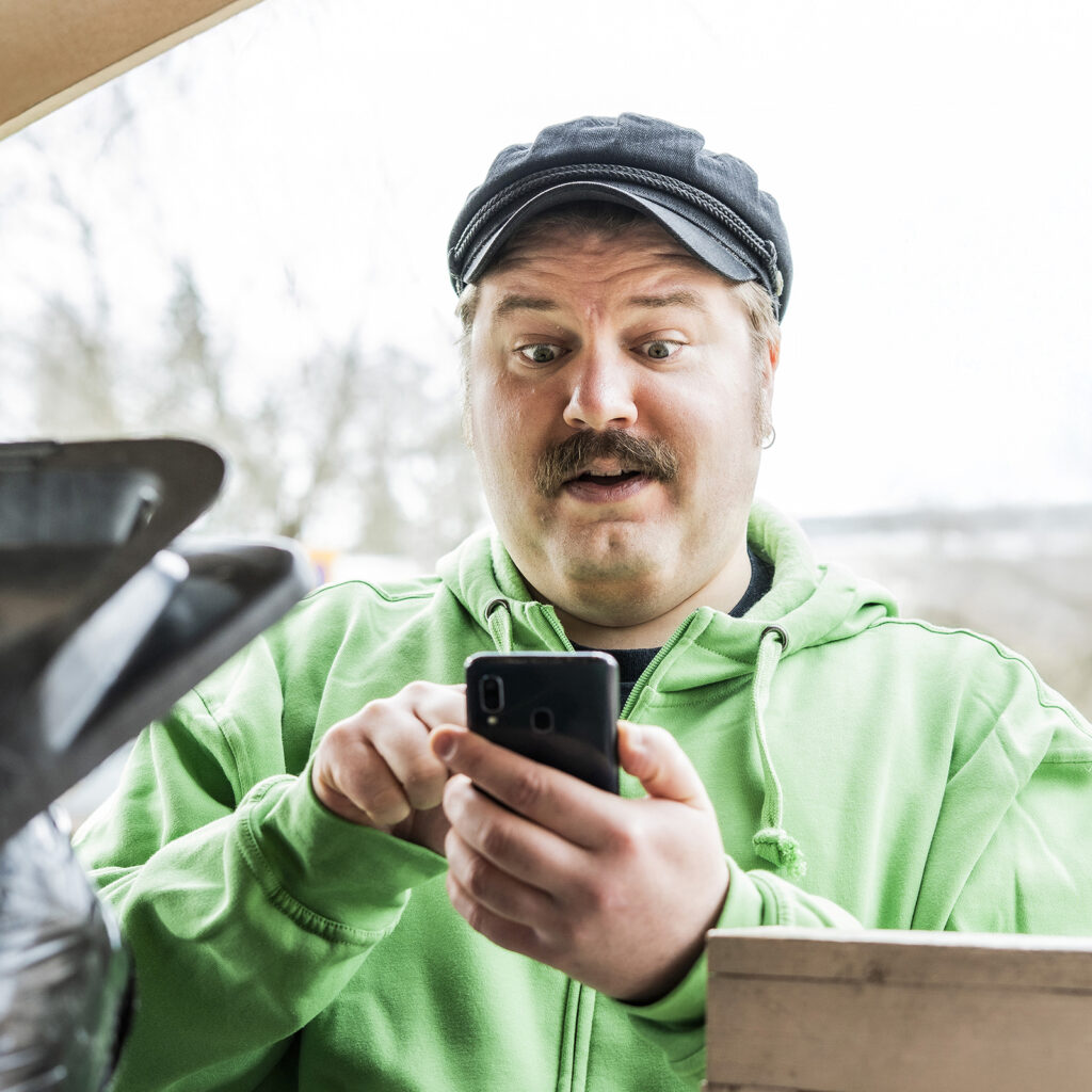 Mies näyttää hämmästyneeltä, kun tuijottaa kännykkäänsä.