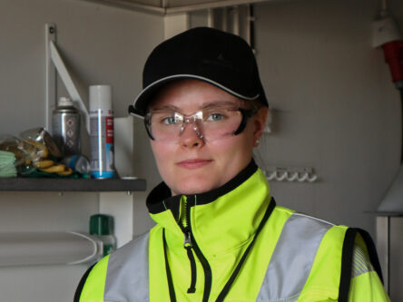 Henkilökuva Salla Leskisestä. Hänellä on päällä keltainen huomiotakki, lippalakki sekä suojalasit.