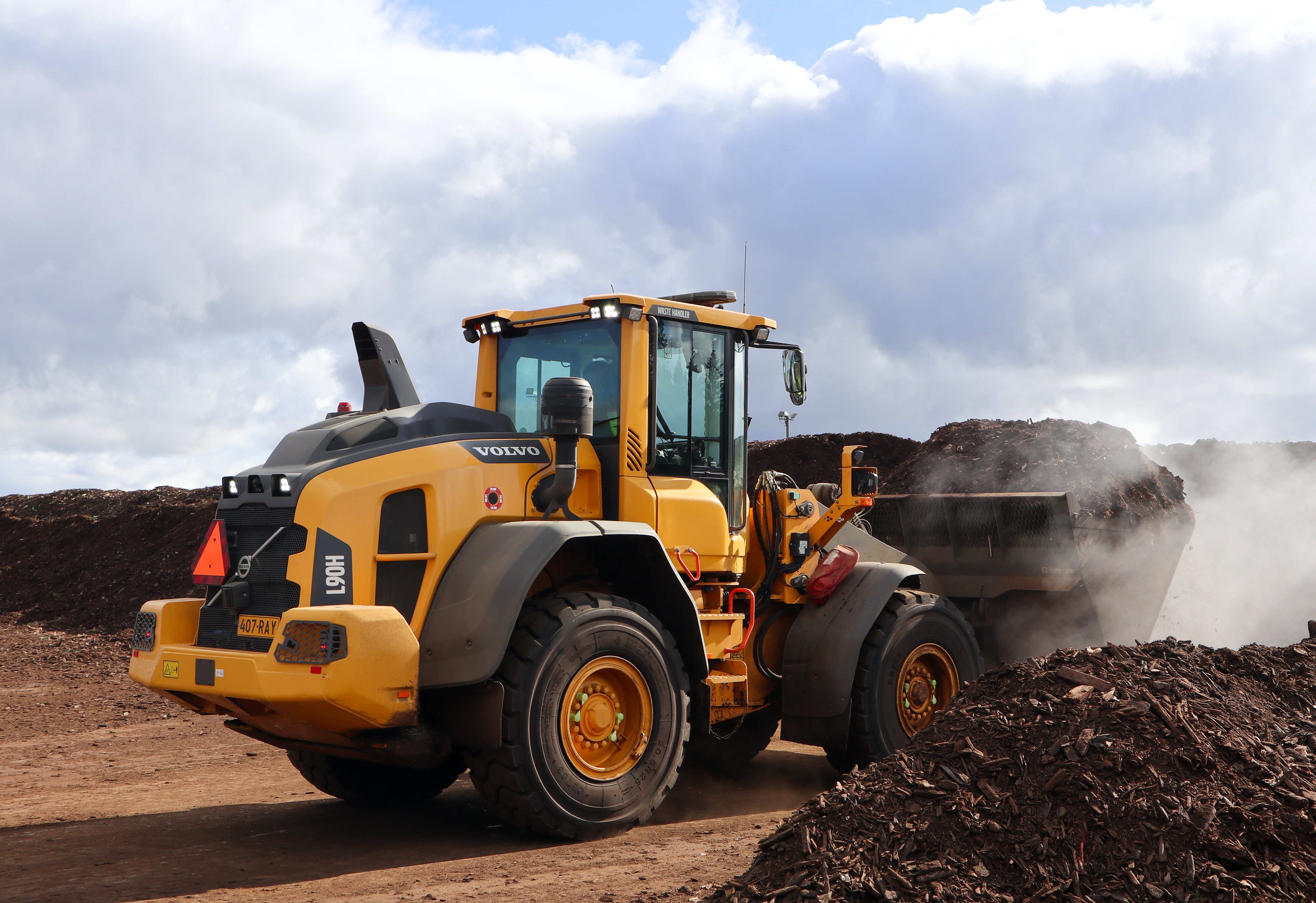 Pyöräkuormaaja ottaa kompostiaumasta kompostia kauhaansa. Taustalla näkyy jätekeskuksen jälkikypsytyskenttä.