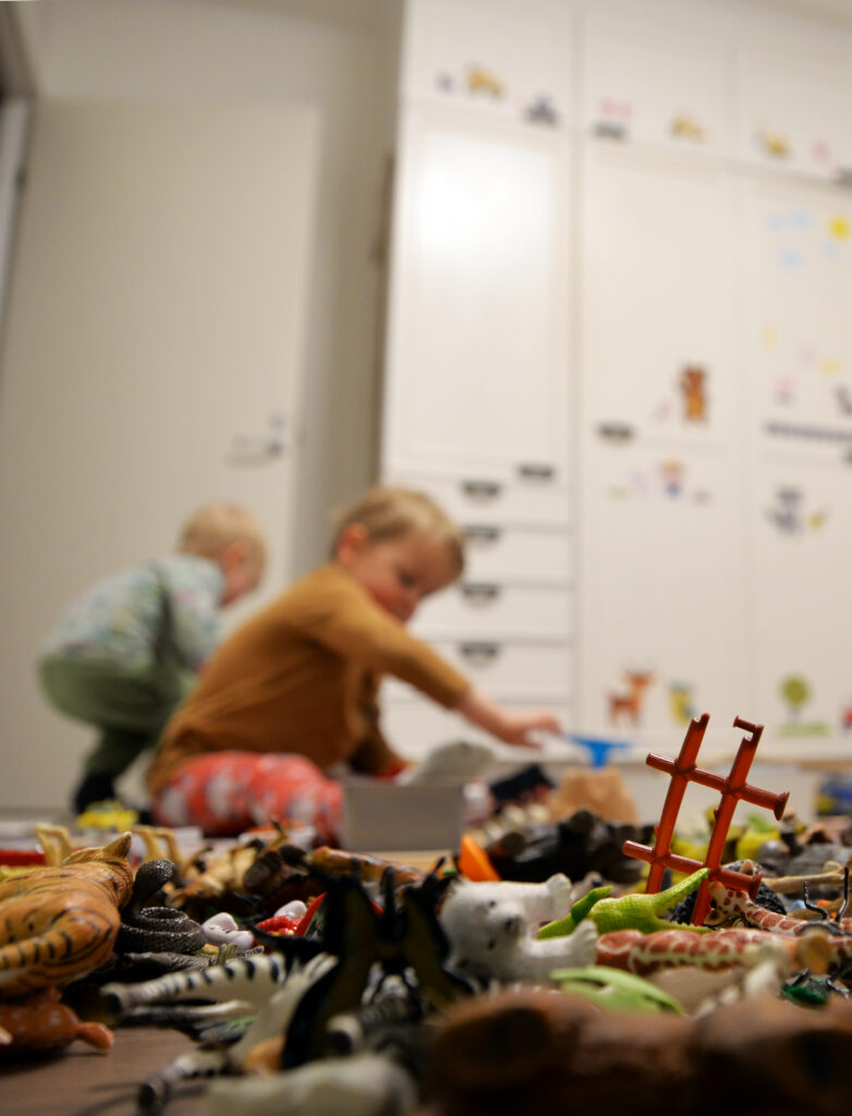 Etualalla on kasa lasten leluja ja takana näkyy epselvästi pari lasta.