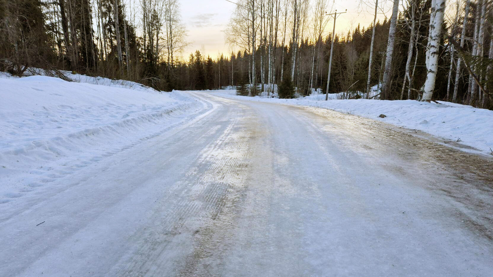 Talvinen tie, joka näyttää todella liukkaalta.