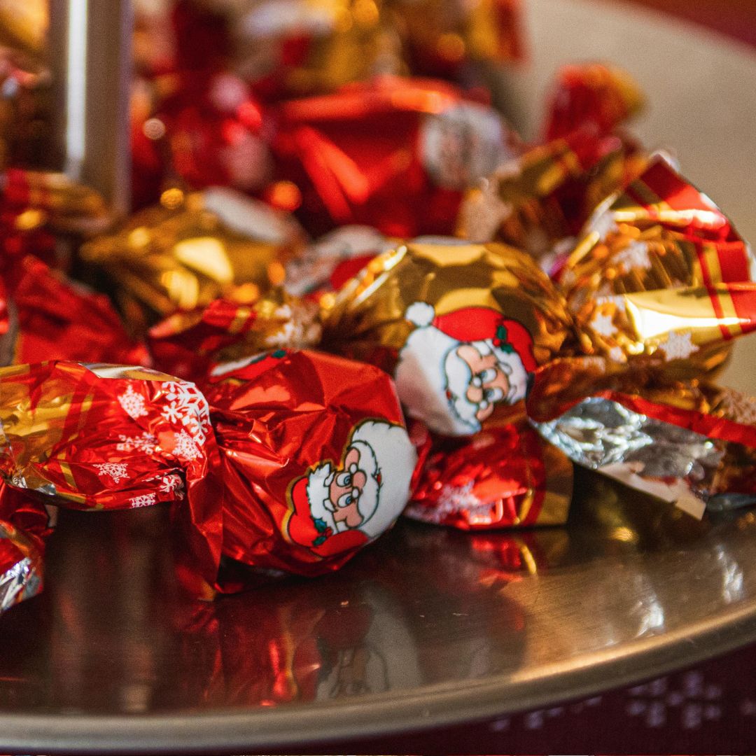 Lautasella on punaisia joulukarkkeja.