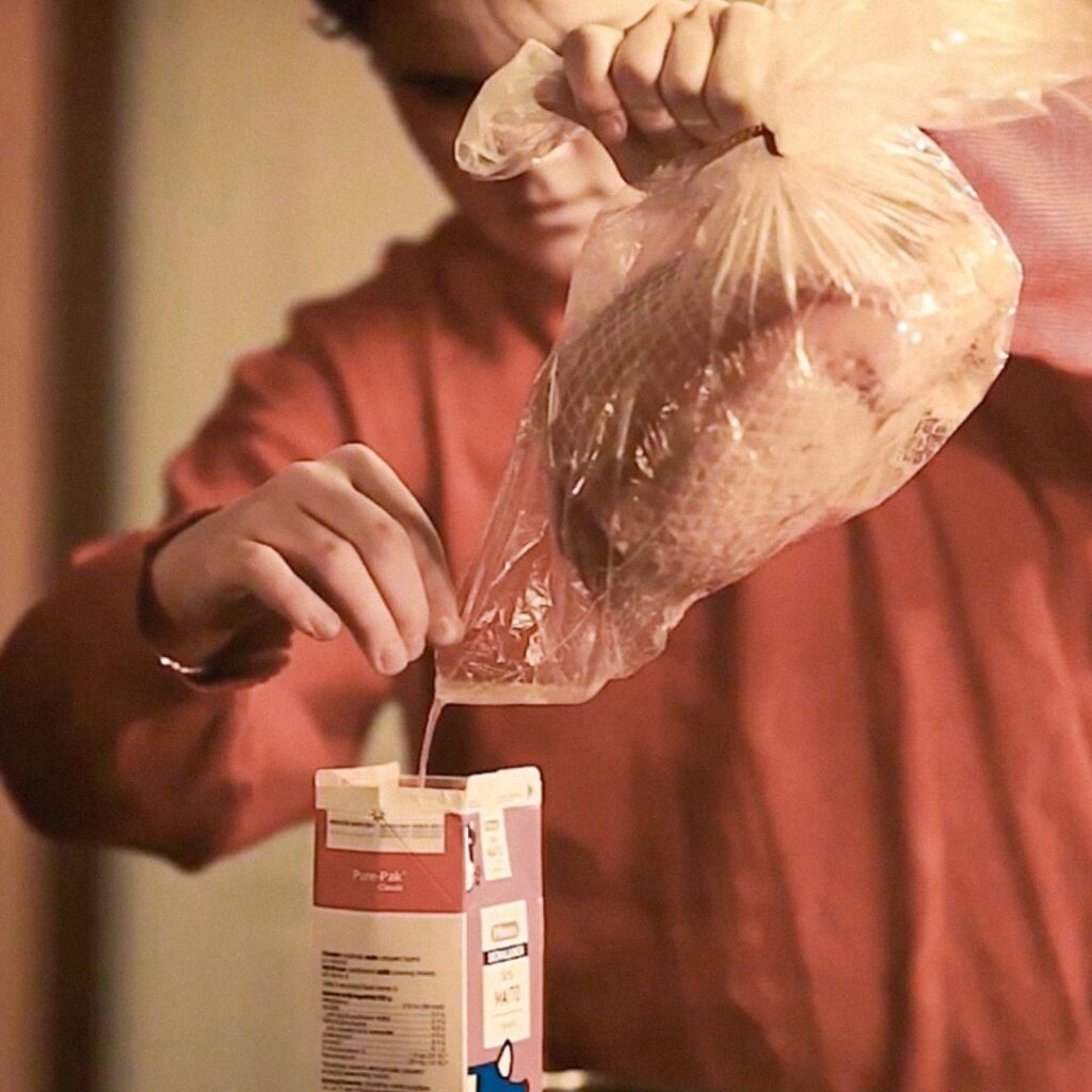 Joulunkinkun paistopussista kaadetaan rasvaa punaiseen maitotölkkiin.