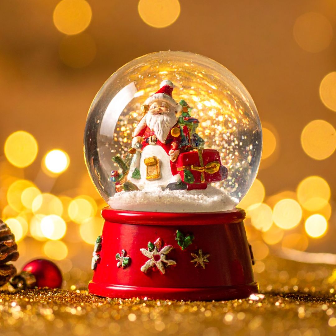 Joulupallo, jossa on sisällä joulupukki lahjojen ja kuusen kanssa.