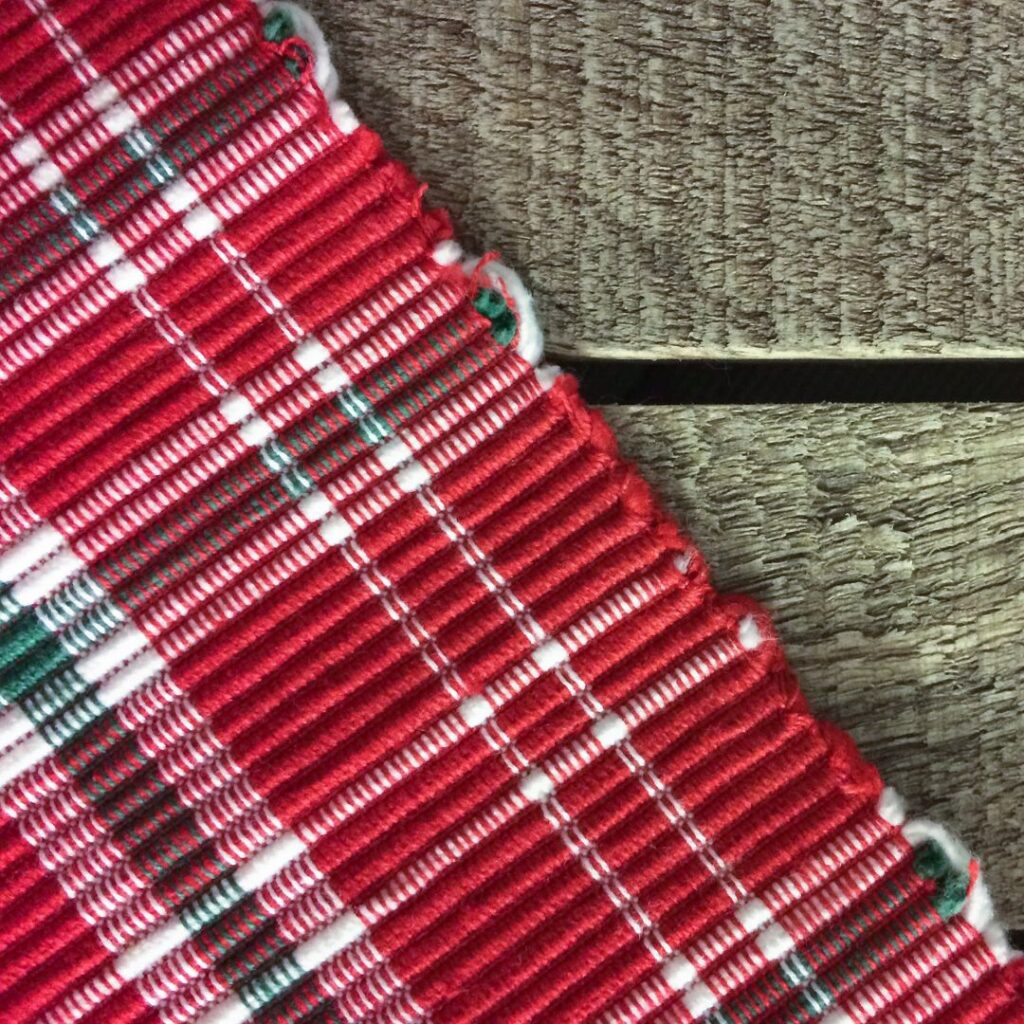 Puista pöytää vasten on punainen pöytäliina, jossa on raitoja.