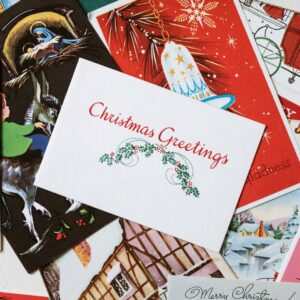 Kasassa on useita joulukortteja, joista päällimmäisessä lukee Christmas Greetings.
