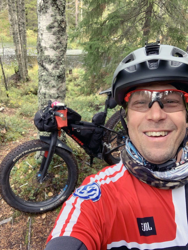 Mies on pyöräilykypärä päässä jossain metsässä pyöräilemässä.