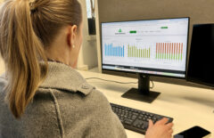 Nainen katselee tietokoneruudulta erilaisia käppyröitä. Hän on jossain toimistossa.