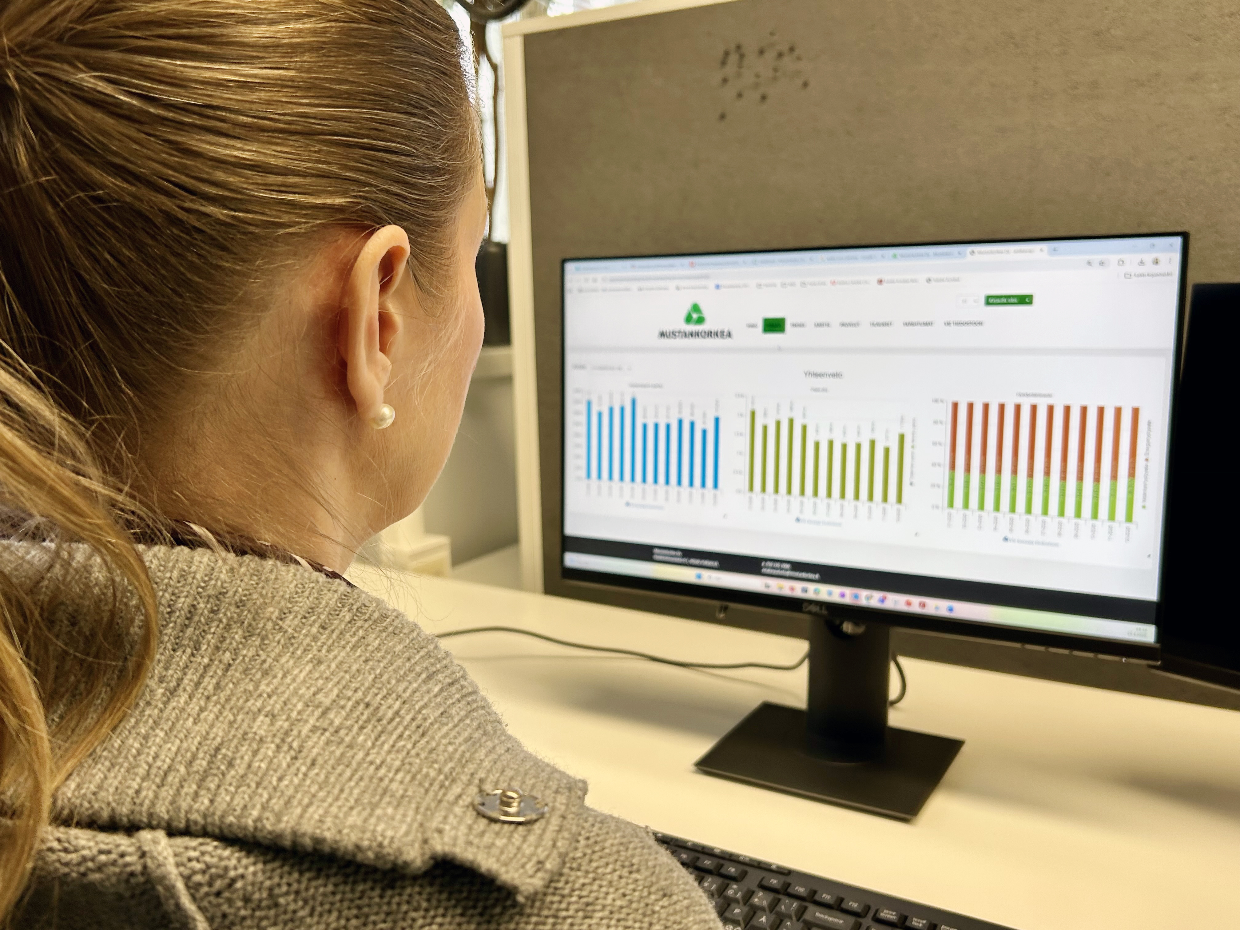 Nainen katselee tietokoneruudulta erilaisia käppyröitä. Hän on jossain toimistossa.