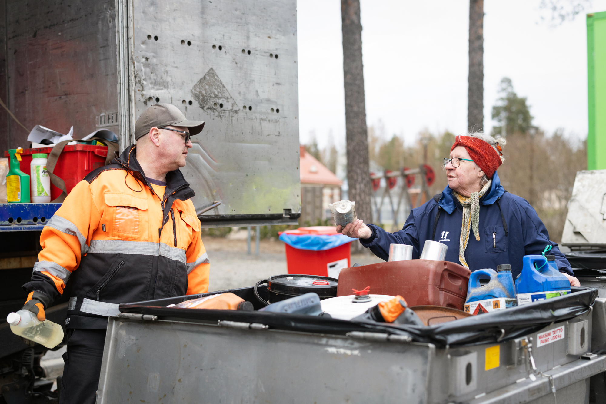 Nainen näyttää huomiotakkiselle miehelle jotain purnukkaa. Edessä on iso astia, jossa on erilaisia purkkeja.