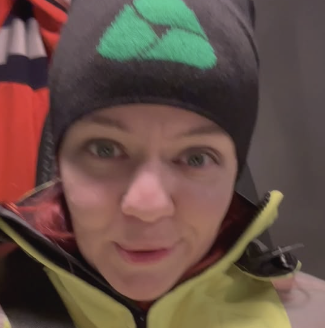 Nainen katsoo kameraan ja hymyilee.