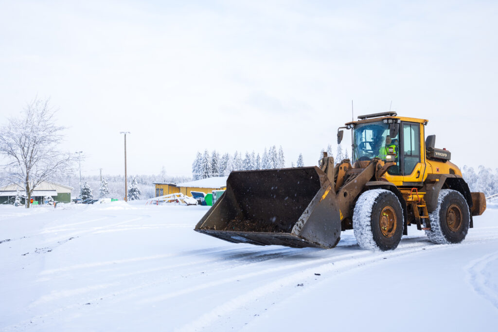 Pyöräkuormaaja kuvattuna lumisella jätepihalla.