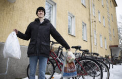 Nuori mies pitää kädessään roskapussia. Taustalla näkyy haalean keltainen kerrostalo.